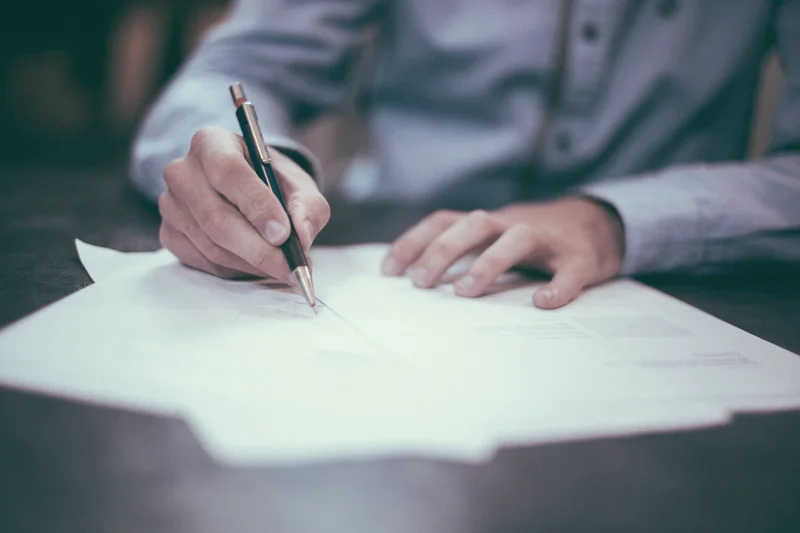 Personne signant un document administratif sur un bureau